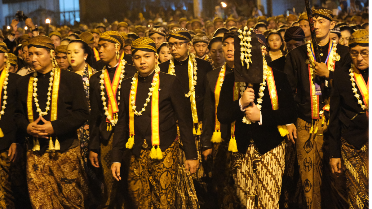 Prosesi Kirab Pusaka Malam 1 Suro di Surakarta, dengan abdi dalem membawa pusaka kerajaan dan diikuti oleh masyarakat dalam suasana sakral.
